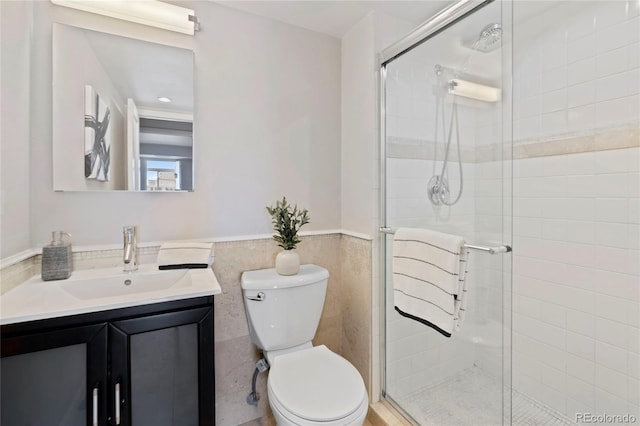 full bathroom featuring a wainscoted wall, toilet, a stall shower, and vanity