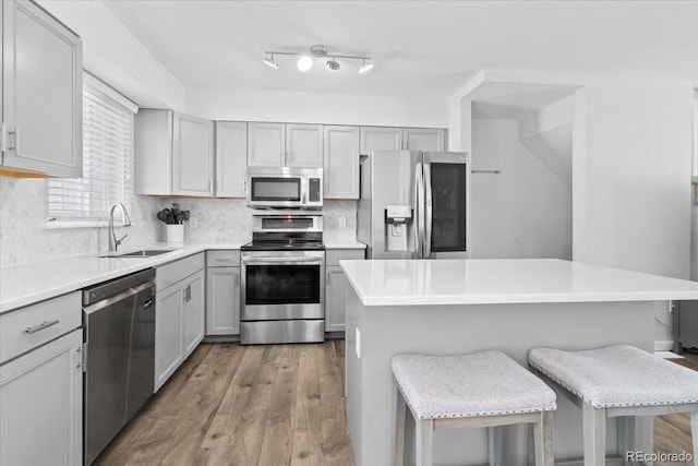 kitchen featuring gray cabinetry, sink, stainless steel appliances, and a kitchen breakfast bar