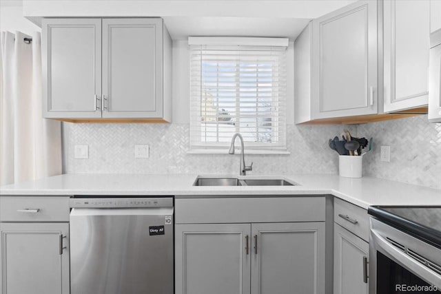 kitchen with stainless steel appliances, gray cabinets, sink, and backsplash