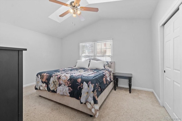 bedroom featuring light carpet, vaulted ceiling with skylight, a closet, and ceiling fan