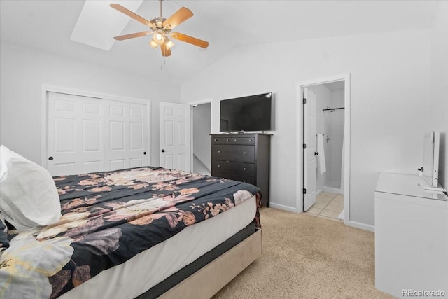 carpeted bedroom with ensuite bath, vaulted ceiling with skylight, a closet, and ceiling fan