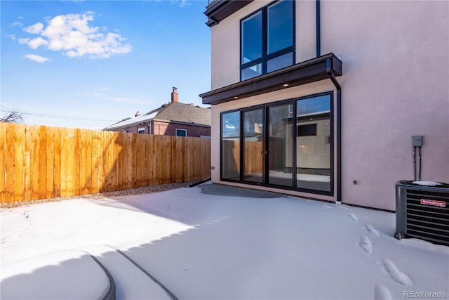 snow covered property featuring central AC unit and a patio area