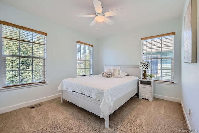 carpeted bedroom with multiple windows and ceiling fan