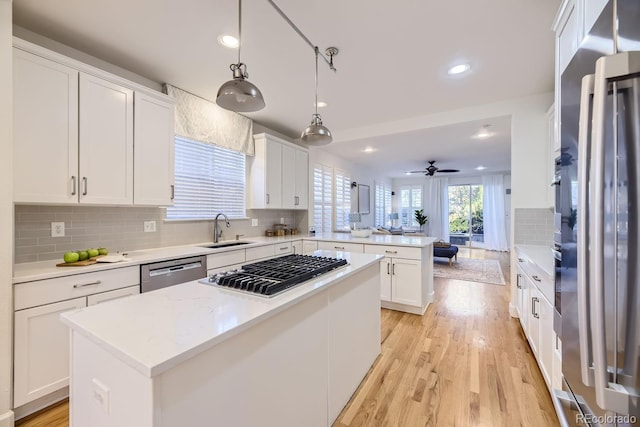 kitchen with a kitchen island, appliances with stainless steel finishes, pendant lighting, sink, and white cabinets