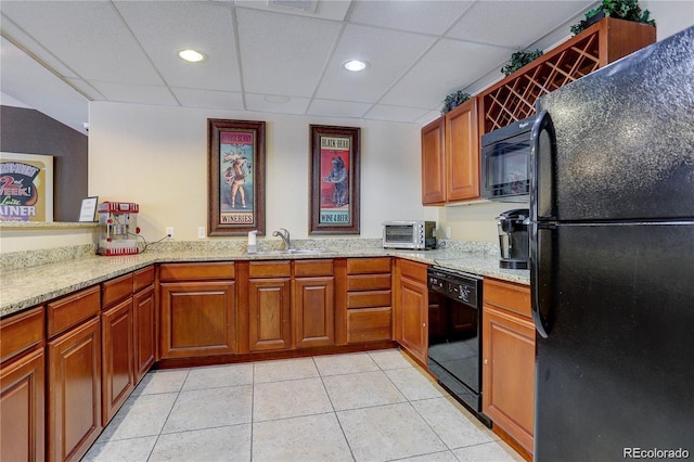 9039 E Panorama Cir Unit C201, Englewood, CO 80112 - kitchen with black appliances, a paneled ceiling, light stone counters, light tile patterned floors, and brown cabinets