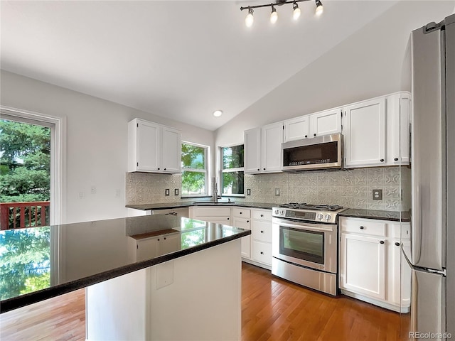 5005 W 128th Pl, Broomfield, CO 80020 - kitchen with stainless steel appliances, dark countertops, white cabinets, tasteful backsplash, and lofted ceiling