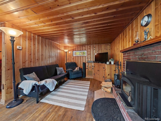 living room with wood walls, hardwood / wood-style floors, a wood stove, and wooden ceiling