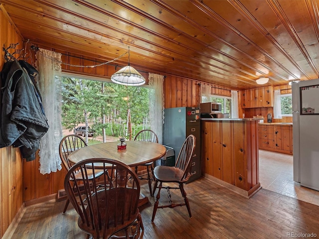 dining space featuring hardwood / wood-style flooring, wood walls, and wooden ceiling