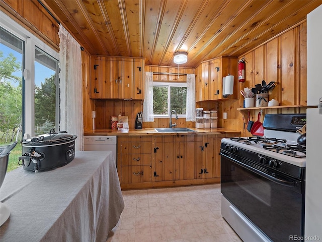 kitchen featuring vaulted ceiling, white appliances, wooden ceiling, wooden walls, and sink