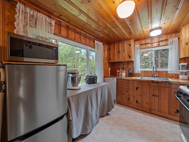 kitchen with stainless steel fridge, dishwasher, wooden ceiling, wooden walls, and sink