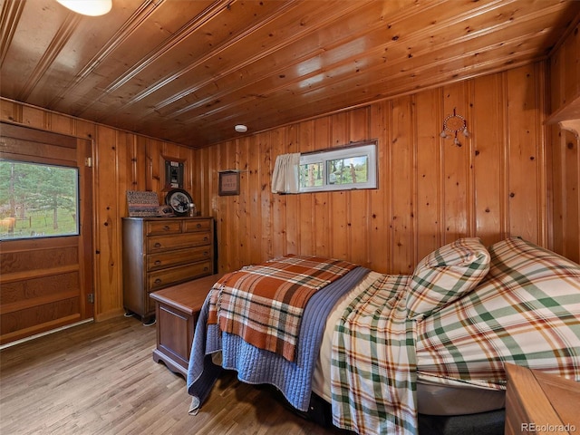 bedroom with multiple windows, light wood-type flooring, wood walls, and wooden ceiling