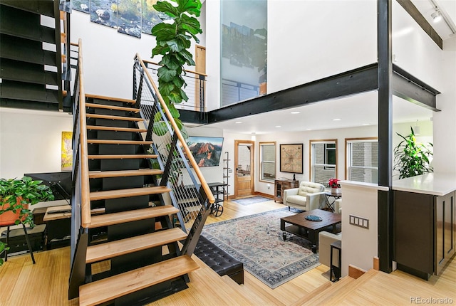 stairs featuring hardwood / wood-style floors, rail lighting, and a high ceiling