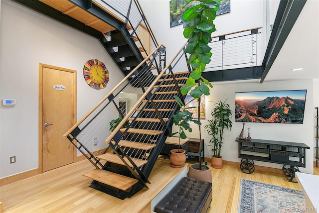 staircase featuring wood-type flooring and a towering ceiling