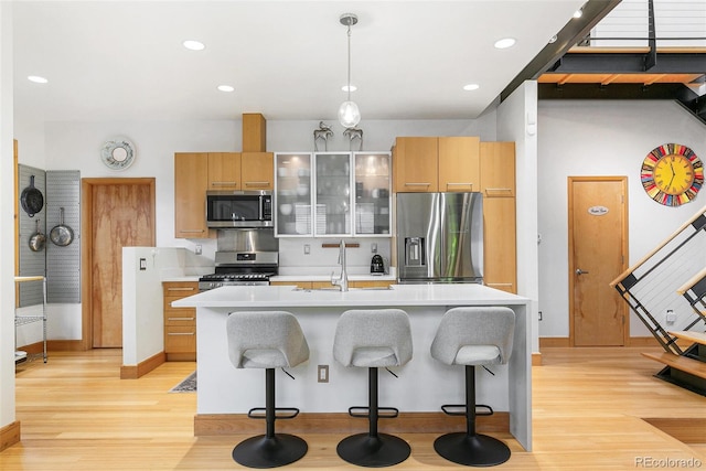 kitchen featuring a kitchen bar, sink, light wood-type flooring, and stainless steel appliances