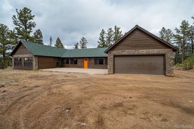 ranch-style house featuring a garage, driveway, and stone siding