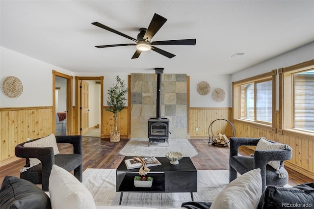 living area with wood finished floors, a ceiling fan, a wainscoted wall, and wooden walls