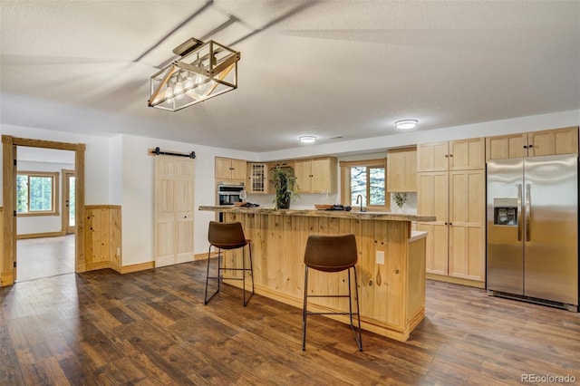 kitchen featuring light brown cabinets, a breakfast bar, a center island, a barn door, and stainless steel appliances