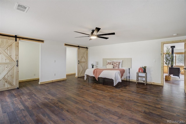 bedroom featuring baseboards, dark wood-type flooring, a barn door, and visible vents