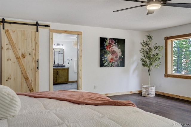bedroom featuring a ceiling fan, wood finished floors, baseboards, a barn door, and a sink