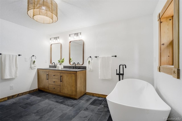 bathroom featuring baseboards, a sink, a freestanding tub, and double vanity