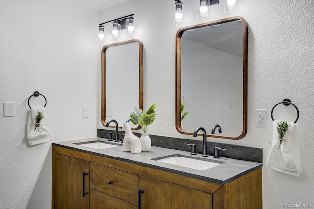 full bathroom featuring double vanity, a sink, and a textured wall