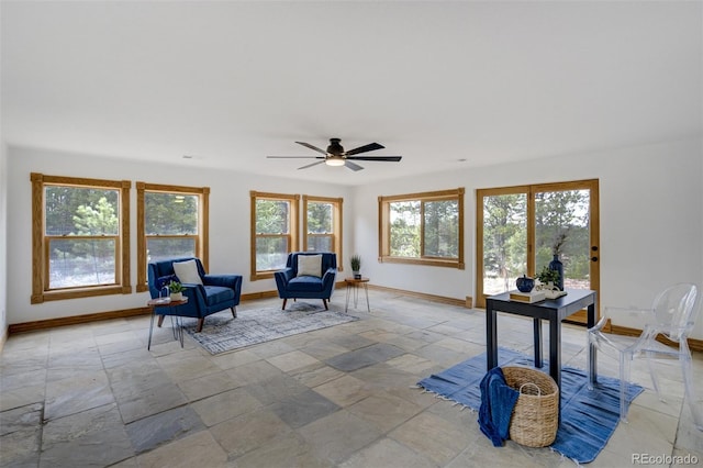 sitting room with baseboards, a healthy amount of sunlight, and stone tile flooring