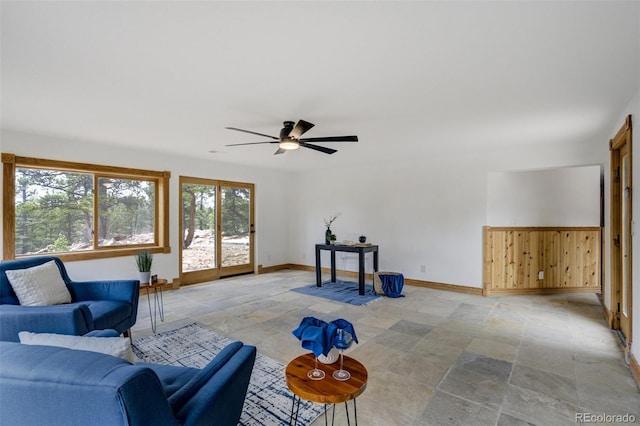 interior space with baseboards, ceiling fan, and stone finish floor