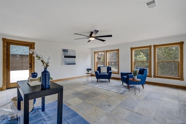 interior space with baseboards, visible vents, a ceiling fan, and stone tile floors
