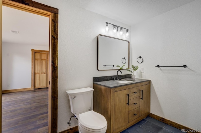 bathroom with visible vents, vanity, wood finished floors, toilet, and baseboards