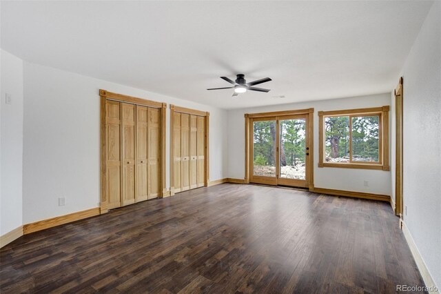 unfurnished bedroom featuring ceiling fan, access to exterior, wood finished floors, baseboards, and two closets