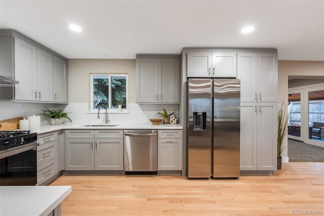 kitchen featuring a sink, light countertops, appliances with stainless steel finishes, gray cabinets, and tasteful backsplash