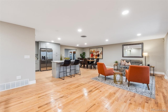 living room featuring light wood-style floors, recessed lighting, visible vents, and baseboards