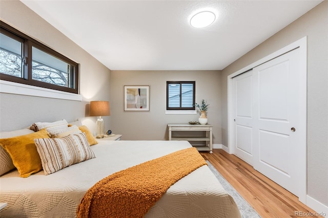 bedroom with baseboards, multiple windows, and light wood finished floors