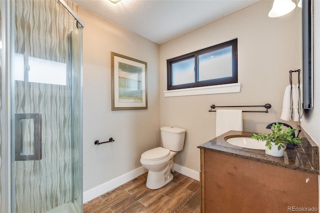 full bath with toilet, wood finished floors, vanity, baseboards, and a shower stall