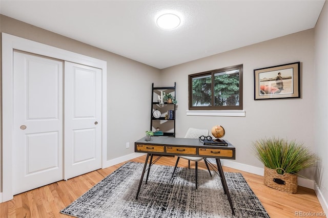 home office with light wood-style flooring and baseboards