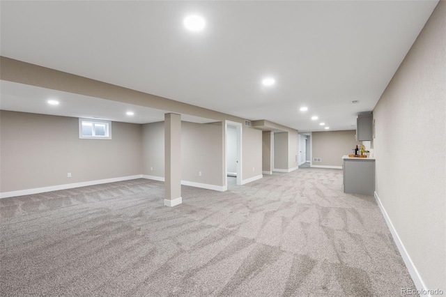 below grade area featuring light carpet, baseboards, and recessed lighting