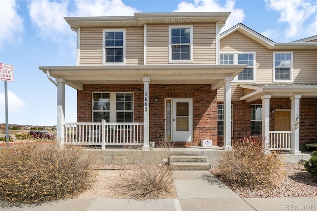 view of front of home featuring covered porch and brick siding