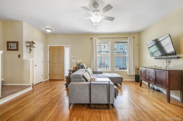 living area featuring baseboards, light wood finished floors, and ceiling fan