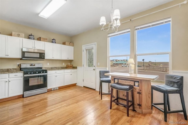 kitchen with pendant lighting, light wood-style floors, white cabinets, a chandelier, and stainless steel appliances