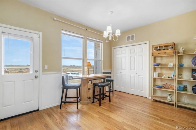 dining room with a chandelier, light wood-type flooring, visible vents, and a wainscoted wall