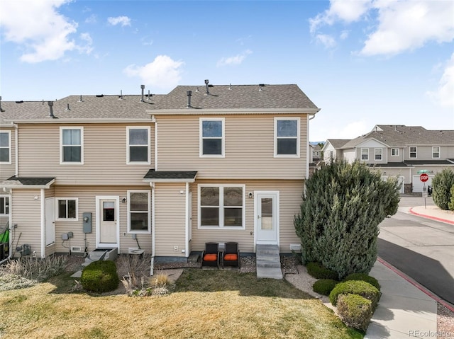rear view of house with a residential view, entry steps, a yard, and roof with shingles