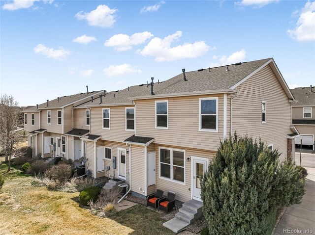 back of house featuring entry steps, cooling unit, a residential view, and roof with shingles