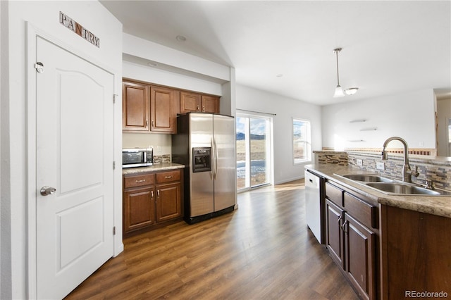 kitchen with appliances with stainless steel finishes, sink, pendant lighting, and dark hardwood / wood-style floors