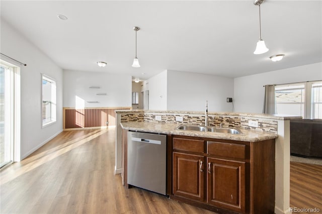 kitchen with dishwasher, sink, pendant lighting, and light hardwood / wood-style flooring