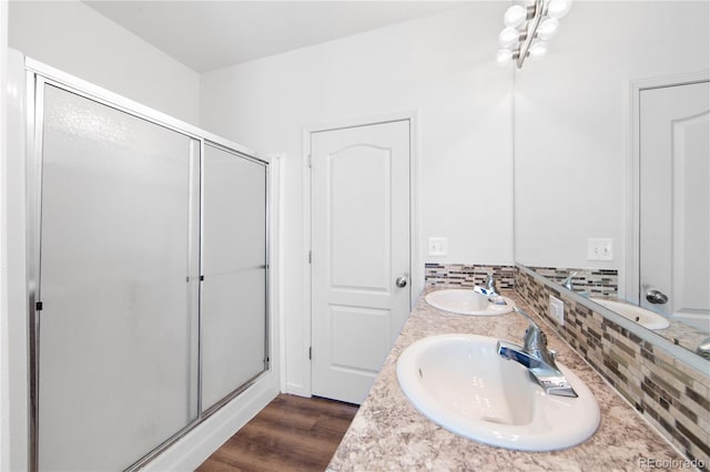 bathroom with hardwood / wood-style flooring, vanity, a shower with shower door, and backsplash