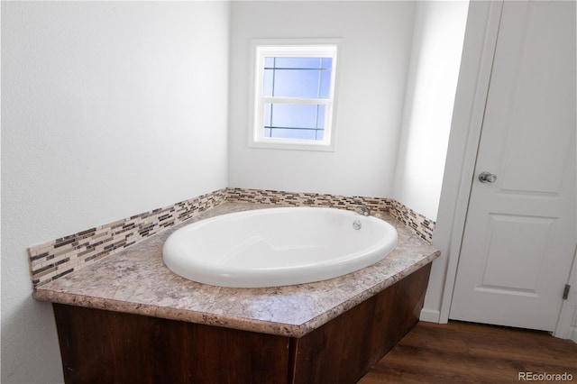 bathroom with a bathing tub, hardwood / wood-style floors, and decorative backsplash