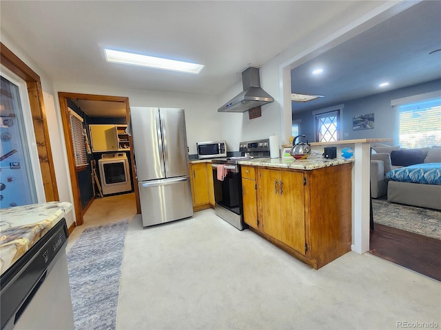 kitchen with kitchen peninsula, stainless steel appliances, wall chimney exhaust hood, and light colored carpet