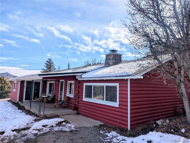 snow covered rear of property with a patio area