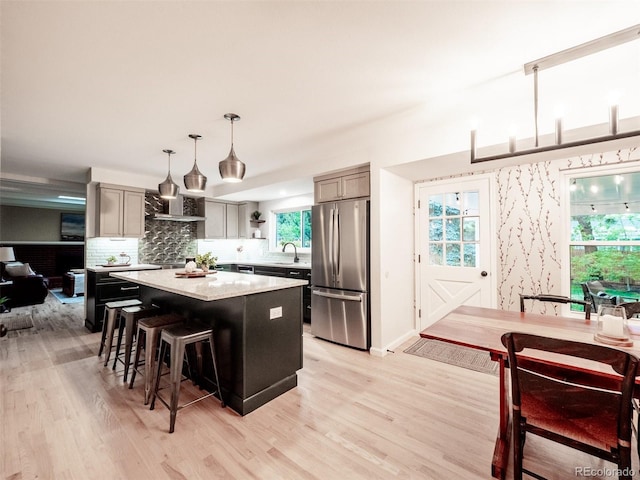 kitchen with freestanding refrigerator, a center island, light wood finished floors, and a kitchen bar