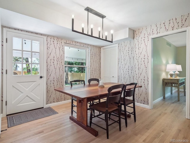 dining room with wallpapered walls, baseboards, and light wood-style flooring